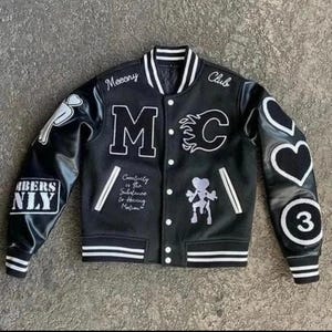 Könnte beinhalten: Eine schwarze Collegejacke mit weißen Details, die den Schriftzug "Meecny Club" und "BERS NLY" auf den Ärmeln trägt. Die Vorderseite zeigt die Buchstaben "M" und "C" mit Flammenmuster, eine kleine Figur und den Text "Creativity is the Substance to Having Motion".