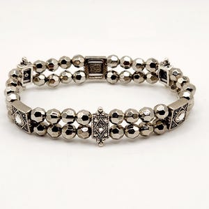 May include: A silver bracelet with faceted beads and decorative accents. The bracelet is double-stranded and has a clasp closure.