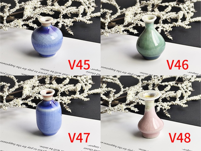 May include: Four small ceramic vases labeled V45, V46, V47, and V48. V45 is a round blue crackle-glaze vase. V46 is a teardrop-shaped green vase. V47 is a cylindrical blue crackle-glaze vase. V48 is a pink vase with a wide, flared rim.
