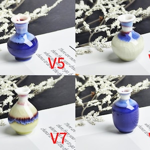 Op de afbeelding: Vier miniatuur keramische vazen gelabeld V5, V6, V7 en V8. V5 en V8 zijn diepblauw met witte randen. V6 is cr&egrave;me met een blauwe hals. V7 heeft een cr&egrave;mekleurige basis, een blauw en paars middengedeelte en een witte rand.