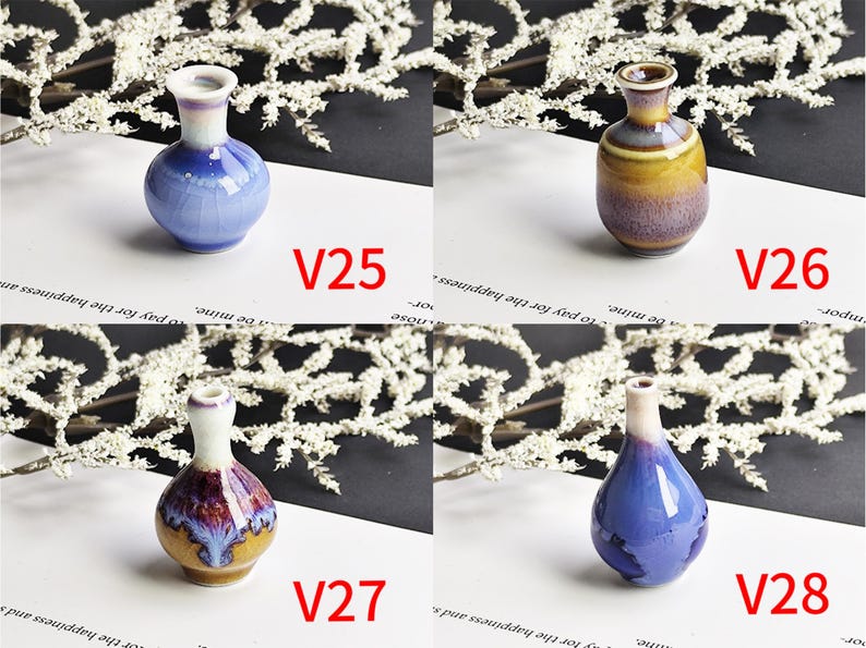 May include: Four small ceramic vases labeled V25, V26, V27, and V28. V25 is blue and white with a crackle glaze. V26 is brown and yellow with a smooth finish. V27 is a bulbous shape with brown, white, and purple tones. V28 is a teardrop shape in blue.