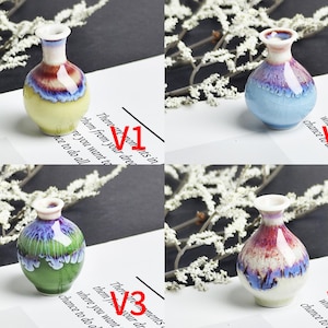 Op de afbeelding: Vier miniatuur keramische vazen met een glanzende, meerkleurige glazuurafwerking. Elke vaas heeft een bolvormig lichaam en een smalle hals met een uitlopende rand. De kleurcombinaties omvatten geel, blauw, groen en rood met een druipglazuureffect.