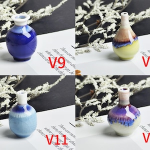 Op de afbeelding: Vier miniatuur keramische vazen gelabeld V9, V10, V11 en V12. V9 is diepblauw met een witte rand. V10 is geel en bruin met een witte hals. V11 is lichtblauw met een wit craquel&eacute; glazuur. V12 is cr&egrave;me, paars en blauw met een witte hals.
