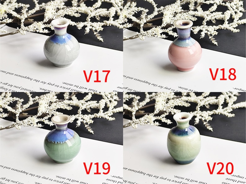 May include: Four small ceramic vases labeled V17, V18, V19, and V20. V17 is light gray, V18 is pink, V19 is light green, and V20 is a taller light green vase. Each features a flared rim and a blue-toned glaze around the neck area.