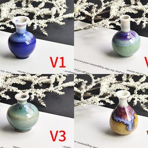 May include: Four miniature ceramic vases labeled V1, V2, V3, and V4. V1 is deep blue, V2 is green and purple, V3 is light teal, and V4 features a yellow, purple, and blue glaze. Each vase has a rounded body, a narrow neck, and a flared rim.