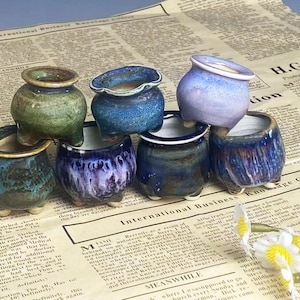 Könnte beinhalten: Ein Set aus drei Keramikbechern mit gesprenkelter, matter Oberfläche. Die Becher sind in den Farbtönen Creme, Hellgrau und Dunkelgrau gehalten. Jeder Becher hat ein schlichtes, minimalistisches Design, ideal für Kaffee oder Tee.