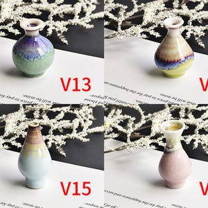 May include: Four miniature ceramic vases labeled V13, V14, V15, and V16. V13 is purple and green, V14 is yellow and purple, V15 is light blue and brown, and V16 is pink and white. Each vase features a narrow neck and a rounded body with a crackle glaze finish.