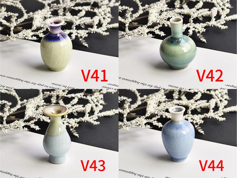 May include: Four small ceramic vases labeled V41, V42, V43, and V44. V41 is cream with a blue rim. V42 is sage green with a floral pattern. V43 has a flared rim and light blue base. V44 is a light blue vase with a crackle glaze finish.