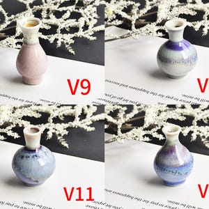 May include: Four small ceramic vases labeled V9, V10, V11, and V12. V9 is light pink with a white neck. V10 is purple and white with a crackle glaze. V11 is light blue and white with a crackle glaze. V12 is a darker blue and purple gradient.
