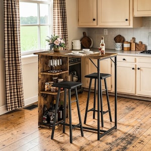 May include: A kitchen island with a dark brown tabletop and black metal frame. It has a built-in storage unit with shelves, wine bottles, and glasses. Two black bar stools are positioned in front of the island, creating a dining area. The island is approx. 100cm in height.