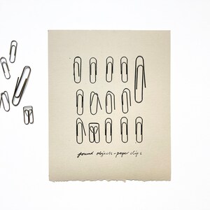 May include: A black and white drawing of paper clips on a beige background. The text "found objects - paper clips" is written at the bottom of the image.