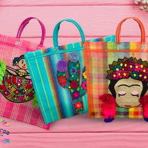 May include: Three vibrant tote bags with embroidered designs. The bags display images of a woman, a cactus, and a dancing figure. Each bag has a different coloured handle and a plaid or striped pattern. The bags are on a pink wooden surface.