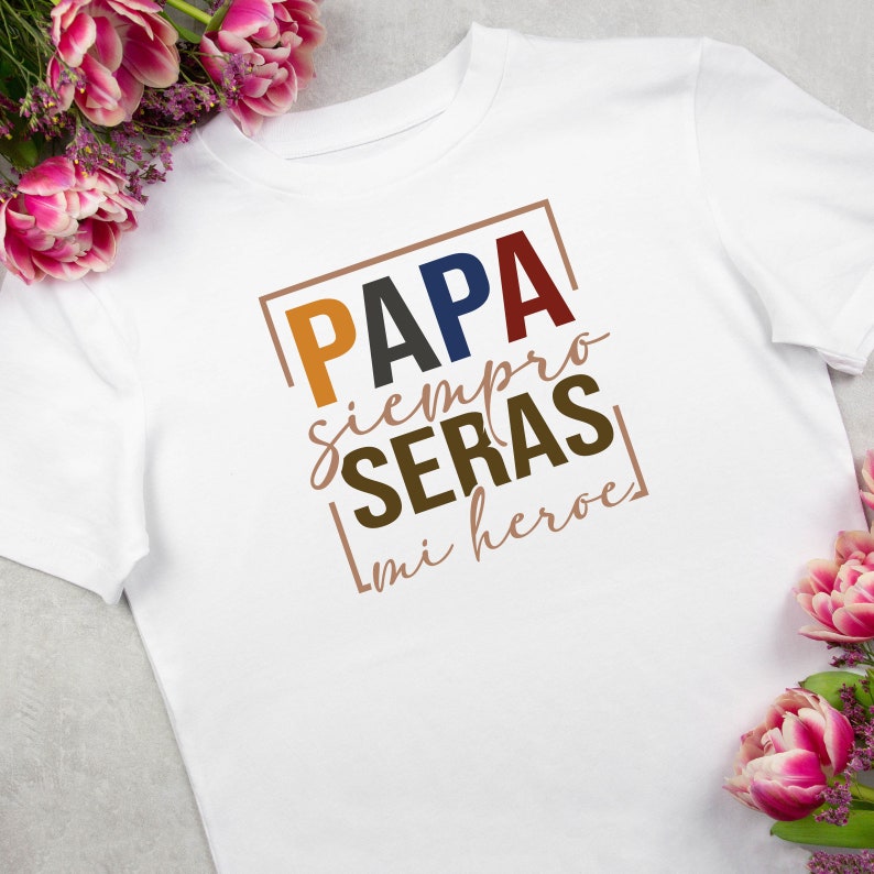 Puede incluir: Camiseta blanca con un gr&aacute;fico colorido que dice "PAPA siempre SERAS mi heroe" en un cuadro.