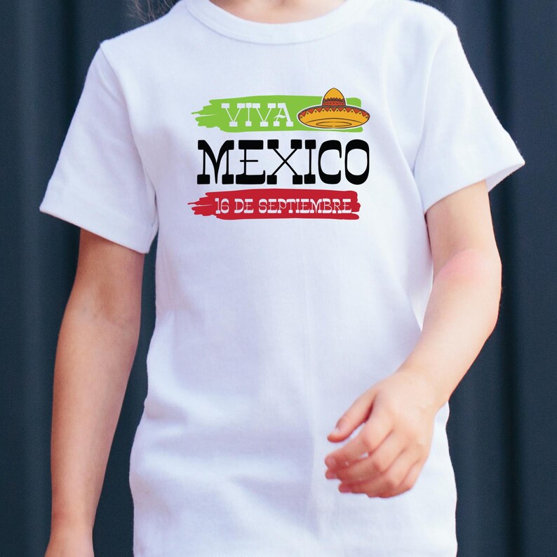May include: White t-shirt with a green, white, and red graphic that says "Viva Mexico" with a sombrero on top and "16 de Septiembre" underneath.