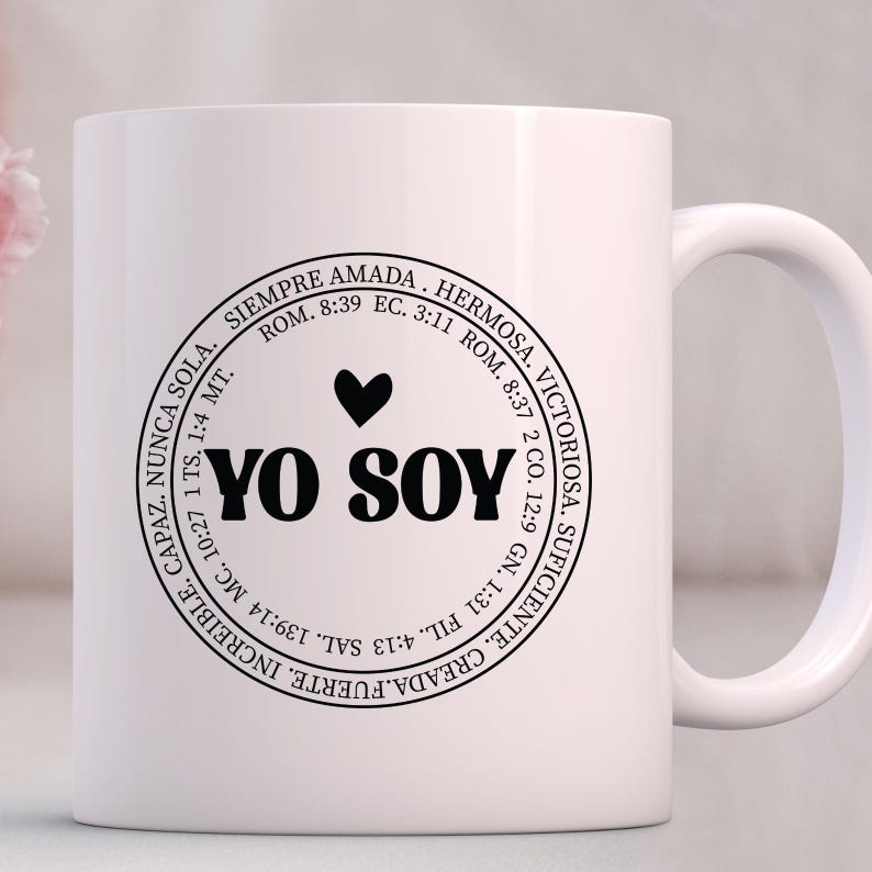May include: White ceramic mug with a black circle design featuring the text "YO SOY" in bold letters, a heart symbol, and a circular border with inspirational text in Spanish.