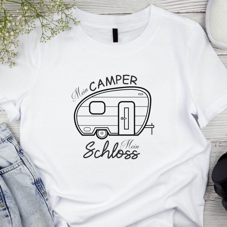 May include: White t-shirt with a black campervan illustration and the German text "Mein Camper Mein Schloss". The design shows a campervan with a door, window, and wheel. The t-shirt is made of a soft, comfortable material.