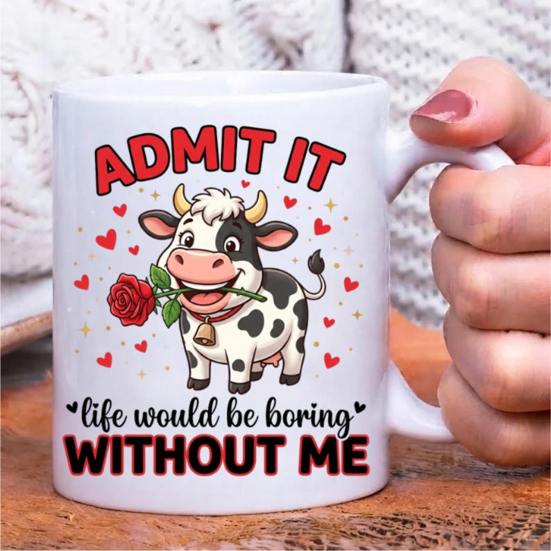 Pode incluir: Uma caneca de cer&acirc;mica branca com uma vaca de desenho animado com manchas pretas, usando um sino e segurando uma rosa vermelha na boca. O texto diz ADMIT IT e life would be boring WITHOUT ME, rodeado por pequenos cora&ccedil;&otilde;es vermelhos e estrelas.