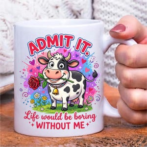 Pode incluir: Uma caneca de cer&acirc;mica branca com uma vaca de desenho animado segurando uma rosa vermelha na boca. O texto diz ADMIT IT. Life would be boring WITHOUT ME. O design inclui salpicos de tinta colorida, cora&ccedil;&otilde;es e flores sobre a relva.