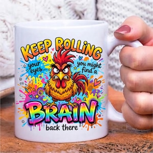 Pode incluir: Uma caneca de cer&acirc;mica branca com um gr&aacute;fico colorido de um galo zangado rodeado por salpicos de tinta vibrantes. O texto diz: KEEP ROLLING your eyes... you might find a BRAIN back there. O design utiliza amarelo, laranja e vermelho.