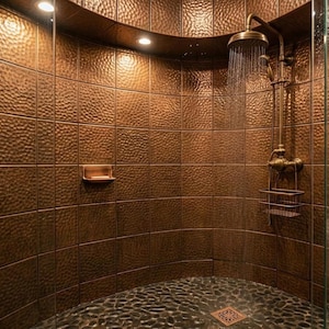 May include: A shower room with copper-toned, textured tiles on the walls. The shower has a vintage-style bronze showerhead and fittings. The floor is made of dark, rounded stones, and the shower is enclosed by a glass door.