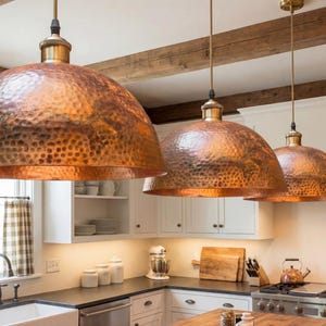 Hand-hammered copper pendant light with a large dome shape and warm reddish-orange metallic finish.