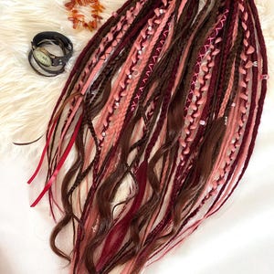 Double-ended dreadlocks in natural shades of chocolate, burgundy, and smoky rose.