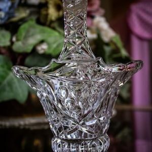 May include: A clear glass basket with a cut glass design. The basket has a handle and a scalloped rim.