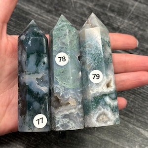 May include: Three moss agate crystal towers with pointed tops. The crystals are primarily green and white, with some areas of dark green and gray. Each tower has a white sticker with a number: 77, 78, and 79.