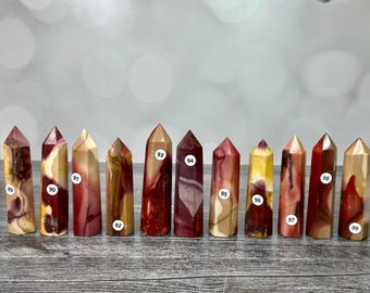 May include: A collection of eleven polished stone towers arranged in a row, each featuring unique patterns of red, yellow, cream, and brown. Each tower is labeled with a small white circular sticker numbered from 89 to 99 on its front surface.
