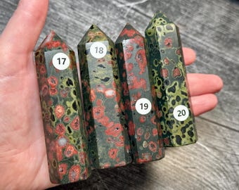 May include: Four polished stone towers with hexagonal points, featuring mottled patterns of dark green, olive, and red spots. Each tower is labeled with a white circular sticker numbered 17, 18, 19, and 20, arranged in a row.