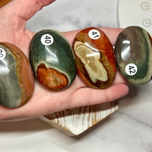 May include: Four smooth, oval-shaped stones with different patterns of green, brown, and red. Each stone is numbered with a white sticker: 39, 40, 41, and 42.