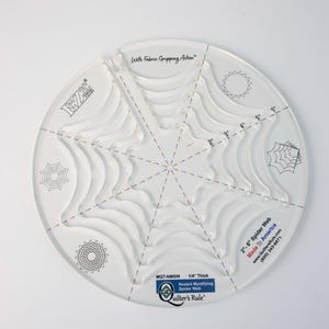 May include: A clear plastic quilting ruler with a spider web design. The ruler has multiple sizes of spider webs, from 2 inches to 6 inches. The ruler is 1/4 inch thick and is made in America. The text "MOT-W Quilter's Rule" is printed on the ruler.
