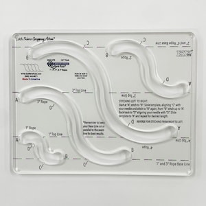 May include: Clear acrylic quilting template with curved and straight lines, labeled with measurements and instructions. Features the text "With Fabric Gripping Action" and "Made in America". Designed for quilting projects.