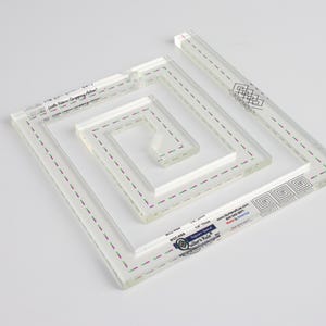 May include: A clear acrylic quilting ruler with multiple square and rectangular frames. The ruler is marked with "Little Fabric Company" and "Quilter's Rule".