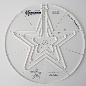 May include: White acrylic quilting ruler with a 6-inch diameter. The ruler features a nested star design with three different sizes: 2 inches, 4 inches, and 6 inches. The ruler also includes a smaller star design in the center.
