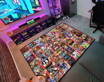 Puede incluir: Una alfombra de juego grande con un collage de varias portadas de videojuegos. La alfombra es negra con un borde rojo y presenta una variedad de títulos de juegos, incluyendo "Crash Bandicoot", "Spyro the Dragon" y "Tony Hawk's Pro Skater".