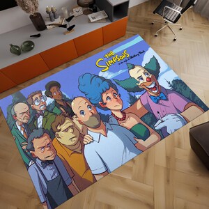 May include: A rectangular area rug featuring a colorful illustration of characters from The Simpsons cartoon. The rug depicts a group of characters, including Krusty the Clown, Marge, and Homer Simpson, with the show's title in yellow.