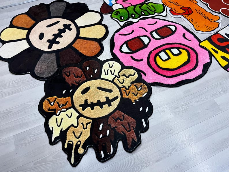 May include: A set of five colorful, cartoon-style rugs. The rugs feature a flower, a face with a big smile, and a face with a frown. The rugs are made of a soft, plush material.