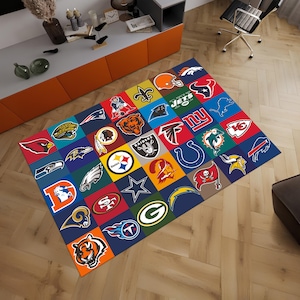 Puede incluir: Una alfombra colorida con un diseño de patchwork que presenta logotipos de diferentes equipos de la NFL. La alfombra está hecha de un material suave y duradero y es perfecta para agregar un toque de fanatismo deportivo a cualquier habitación.