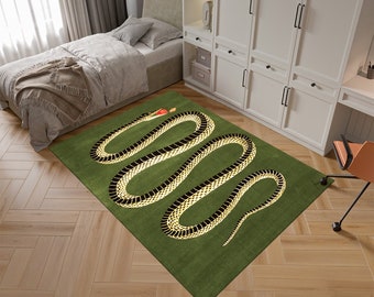 Puede incluir: Una alfombra verde con un diseño de serpiente negra y dorada. La serpiente está enroscada en un círculo y tiene una manzana roja en la boca.