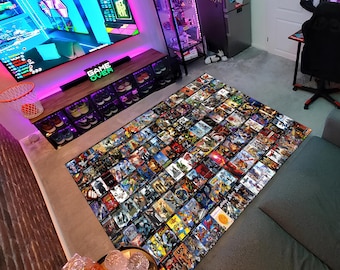 Puede incluir: Una alfombra grande con un patrón colorido de cientos de portadas de videojuegos. La alfombra está colocada sobre una alfombra gris en una habitación con una configuración de juego. La alfombra es una excelente manera de agregar un toque de color y personalidad a cualquier habitación.