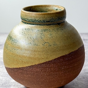 Jarrón pequeño redondo de cerámica artesanal con forma de esfera y aspecto natural.