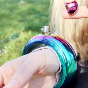 May include: A rainbow-coloured stainless steel flask with a screw-on lid. The flask is shaped like a bracelet and can be worn on the wrist.