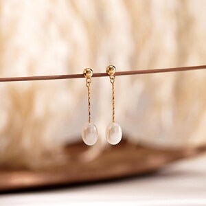 May include: A pair of gold drop earrings with a single white pearl on each earring.