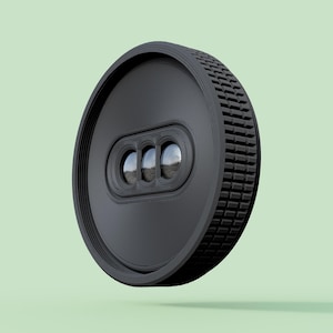 May include: A black, circular device with a textured edge and three lens-like features. The device has a ridged design on the front and a series of small, square-like textures around the side. The background is a solid, light green color.