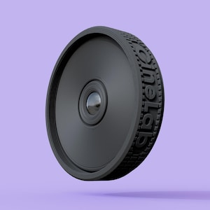May include: A black, circular object with the text "oneLab" embossed on the side. The object has a textured rim and a central lens-like feature. The background is a solid lilac colour.