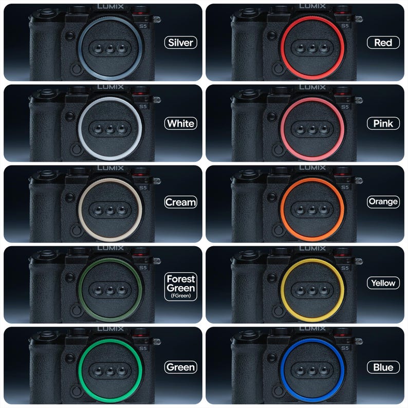 May include: A collection of black Lumix S5 cameras, each featuring a different colored accent ring around the lens: silver, red, white, pink, cream, orange, forest green, yellow, green, and blue. Each camera has the Lumix logo.