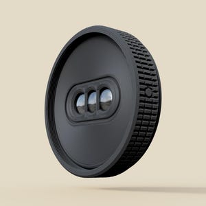 May include: A black, circular device with a textured edge and three reflective lenses. The device has a series of concentric rings on its face and a small button on the side. The background is a solid, neutral color.