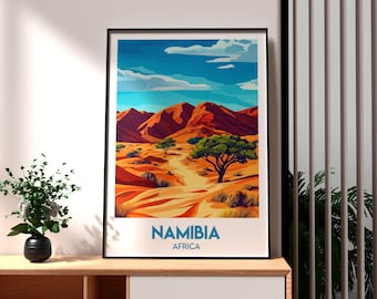 Puede incluir: Una ilustración colorida de un paisaje desértico en Namibia, África. La imagen presenta montañas de color marrón rojizo, un camino de tierra y un árbol verde. El texto "NAMIBIA" y "AFRICA" está impreso debajo de la imagen.