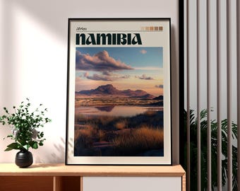 Puede incluir: Impresión artística enmarcada que presenta un paisaje de Namibia, África. La impresión muestra una vista panorámica de montañas, un cuerpo de agua y hierba alta bajo un cielo nublado. La palabra "Namibia" está impresa en negrita, en verde oscuro.